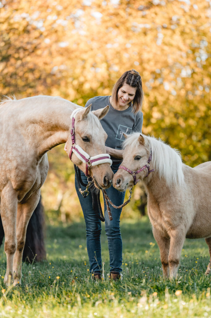 Zwei helle Pferde mit Therapeutin